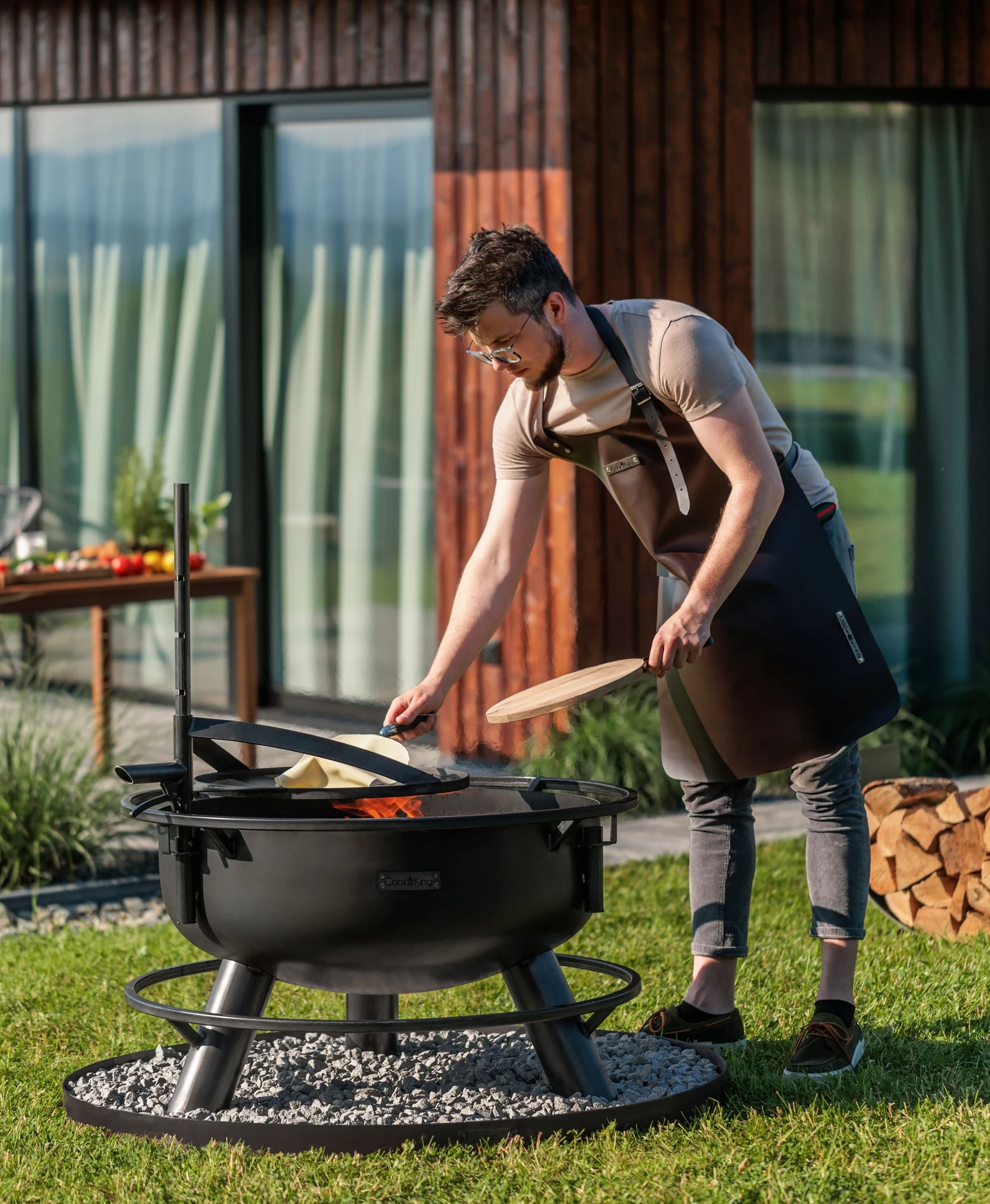 Cooking on a COOK KING fire bowl with a griddle plate in front of a house