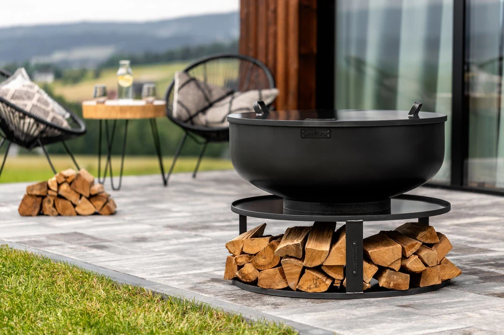 COOK KING fire bowl on a base with a log store on a terrace